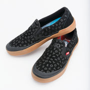 Black slip-on shoes with patterned design and red label on a white background